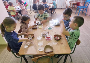 Dzieci przy stoliku pakują swoje czekoladowe serca w celofan